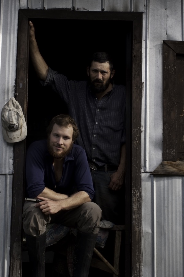 Two weathered men in the doorway of a corrugated-tin cabin, Patagonia
